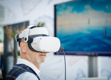 A man wearing a virtual reality headset in front of a laptop