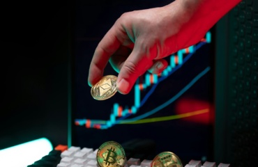 Hand holding ethereum with crypto graphs in background.