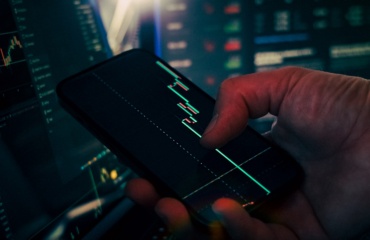 Trader analyzing stock market data on smartphone and phone