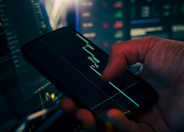 Trader analyzing stock market data on smartphone and phone