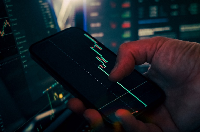 Trader analyzing stock market data on smartphone and phone