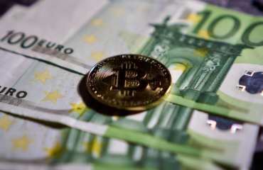 a bitcoin sitting on top of a pile of money