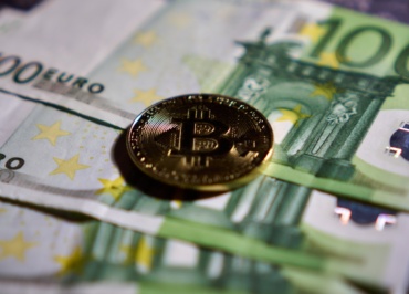 a bitcoin sitting on top of a pile of money