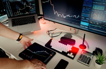 A man sitting at a desk with two monitors and a laptop