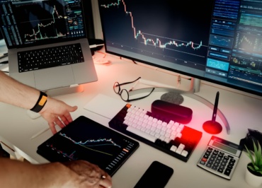 A man sitting at a desk with two monitors and a laptop
