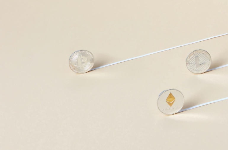 Minimalist studio shot of Bitcoin, Ethereum, and Litecoin coins aligned for a conceptual finance image.