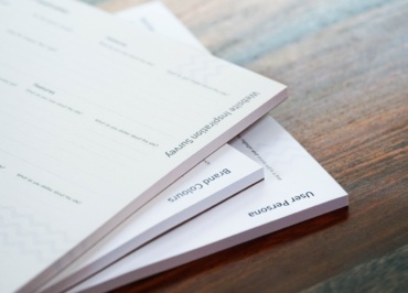 a stack of papers sitting on top of a wooden table