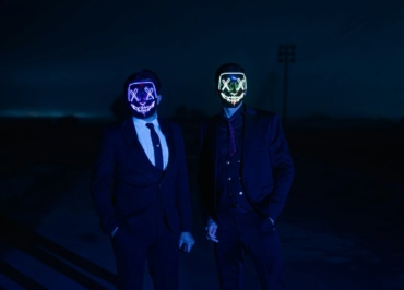 two people wearing masks standing in the dark
