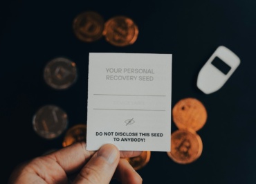a person holding a business card in front of a pile of coins
